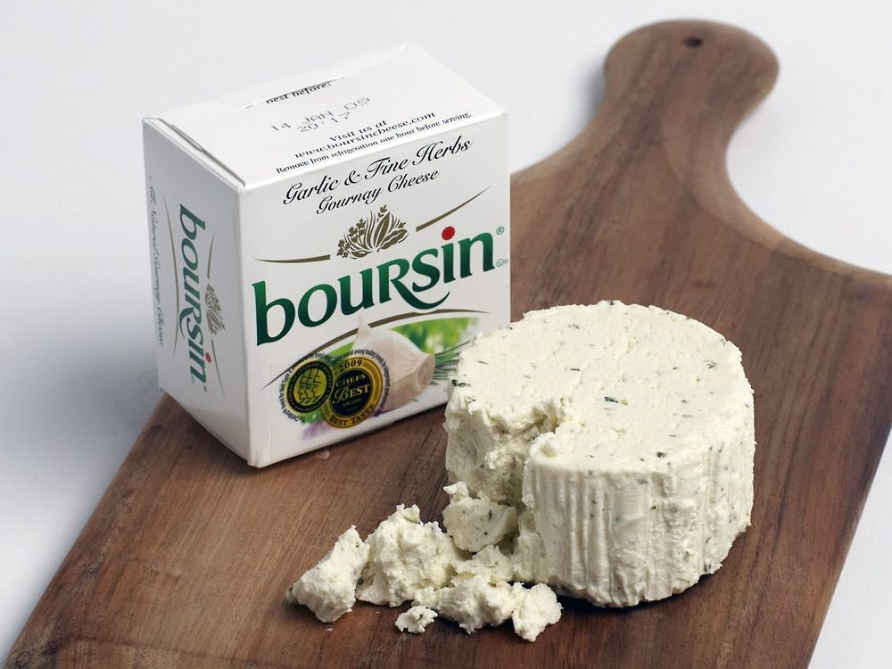 Fresh cream cheese with garlic and herbs Boursin on a wooden paddle