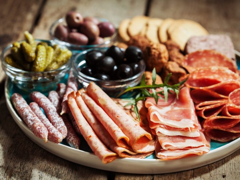 Board of cold charcuterie meats with olives and gherkins