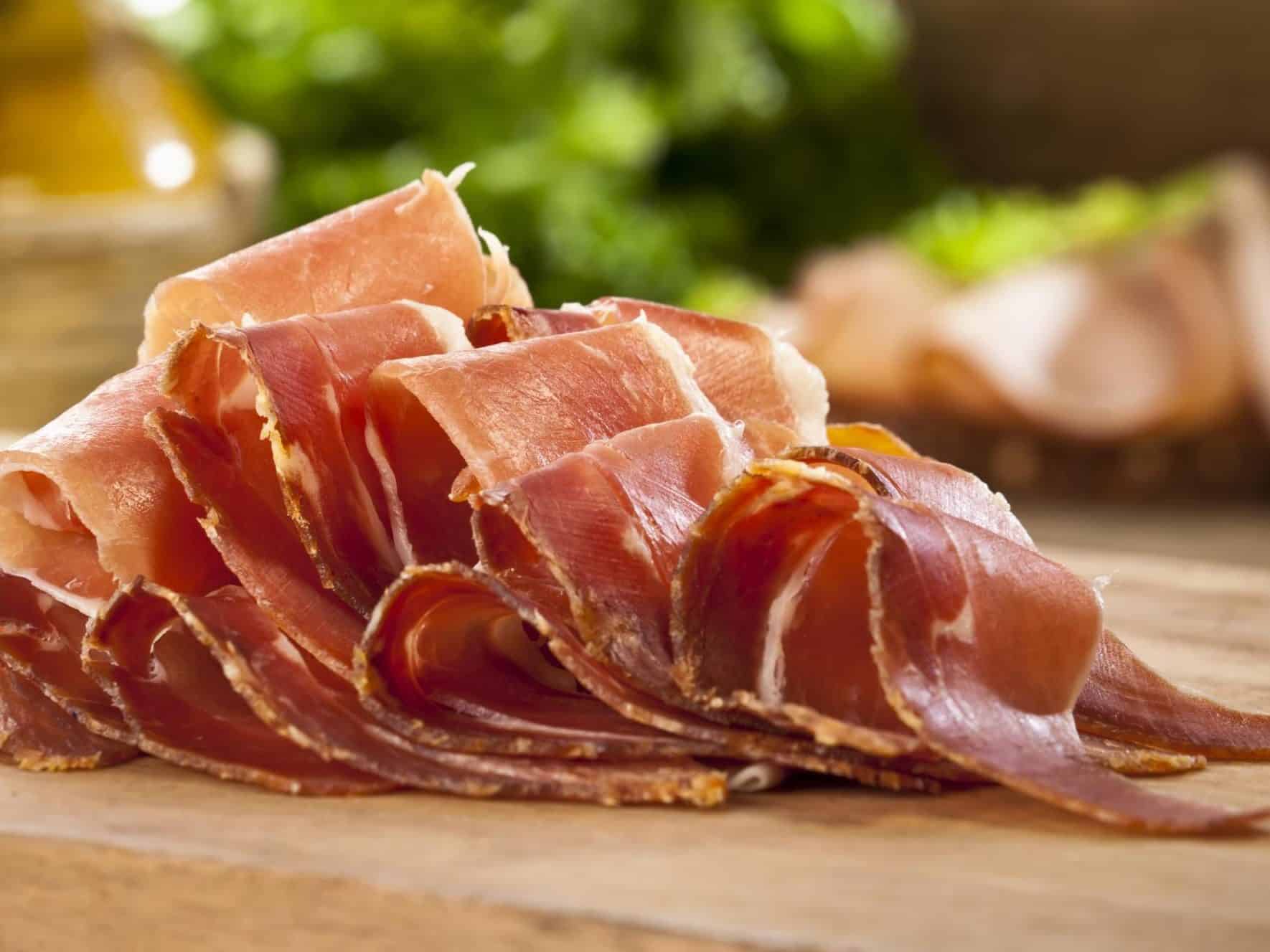 Thin slices of Prosciutto on wooden board