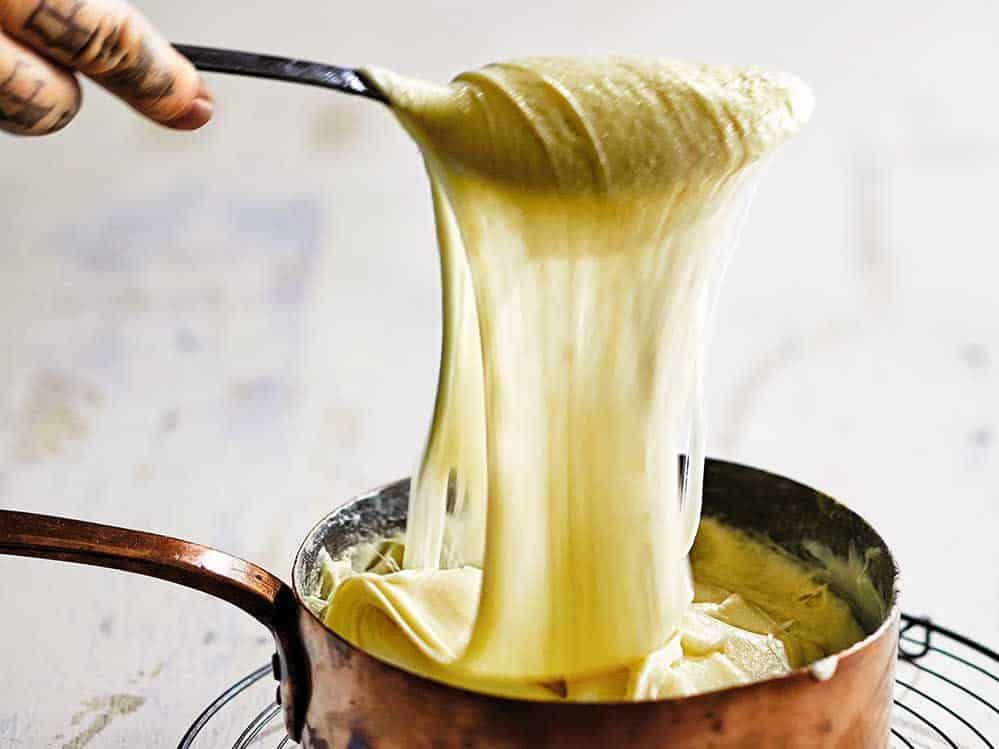 Cheesy mash aligot being pulled from a frying pan