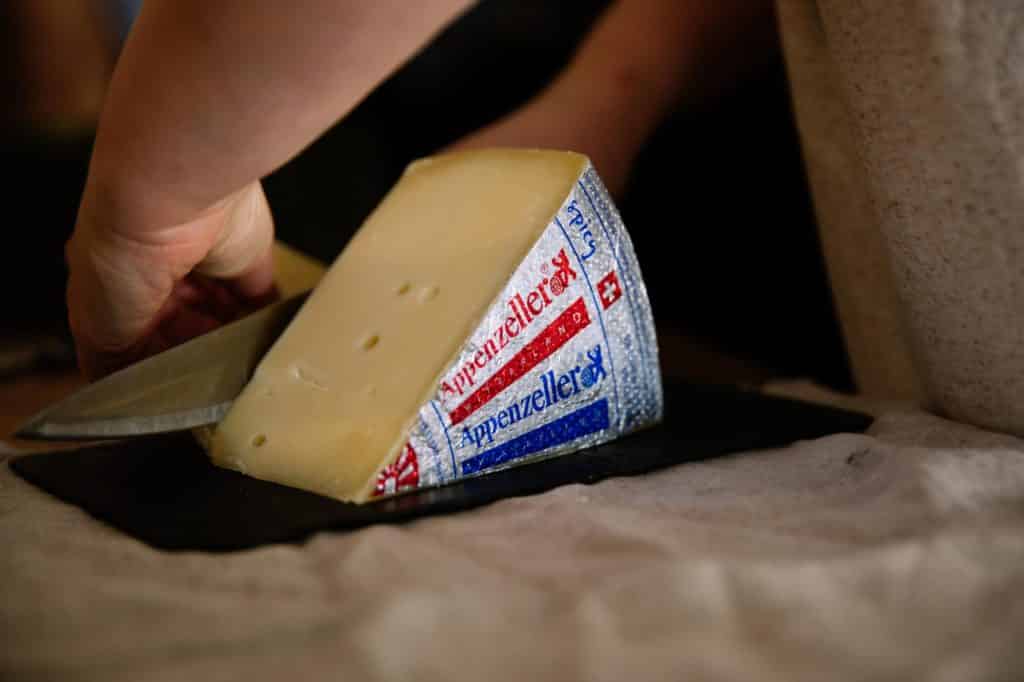 Wedge of Swiss pressed cheese Appenzeller being cut