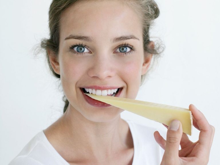 Young woman biting into hard cheese tingling mouth