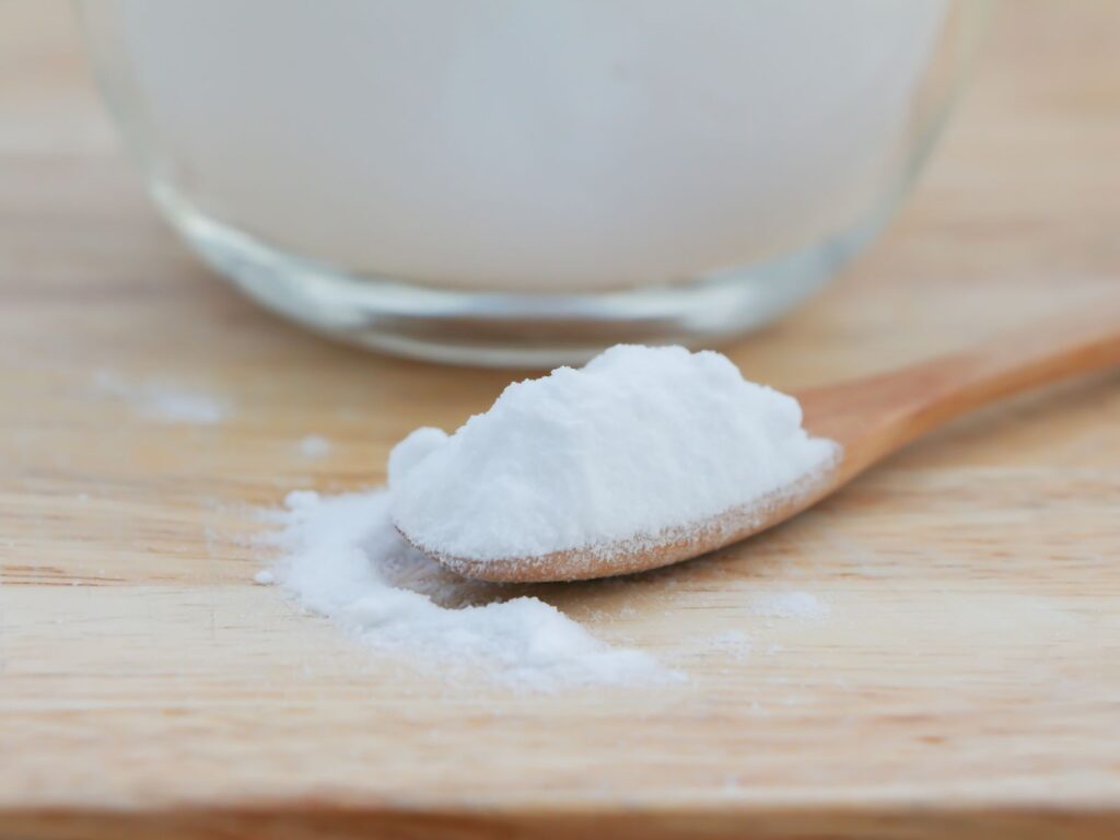 Heap of white crystalline sodium citrate in wooden spoon