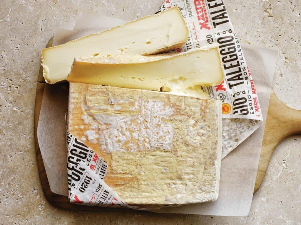 Brick of Taleggio Italian washed rind cheese wrapped in newspaper