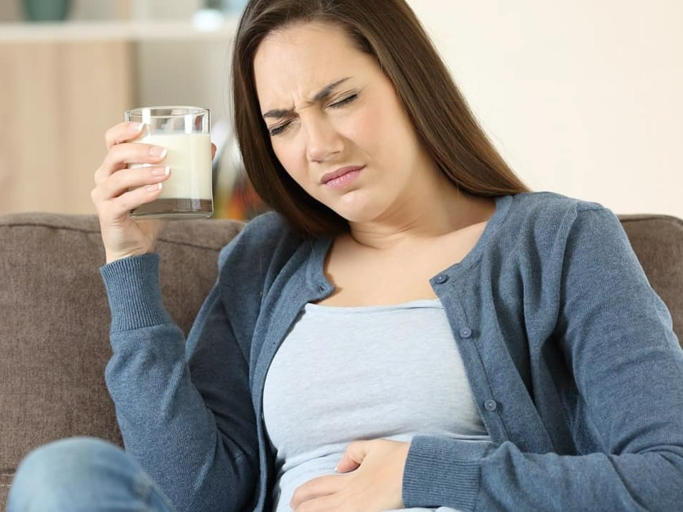 Lactose intolerant female experiencing pain from drinking milk