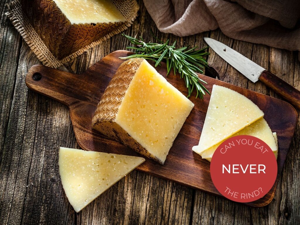 Wedge of Manchego cheese on a wooden board with rosemary and knife