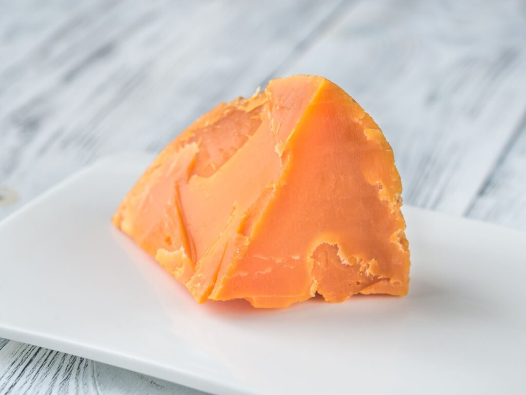 Wedge of orange Mimolette cheese on a board
