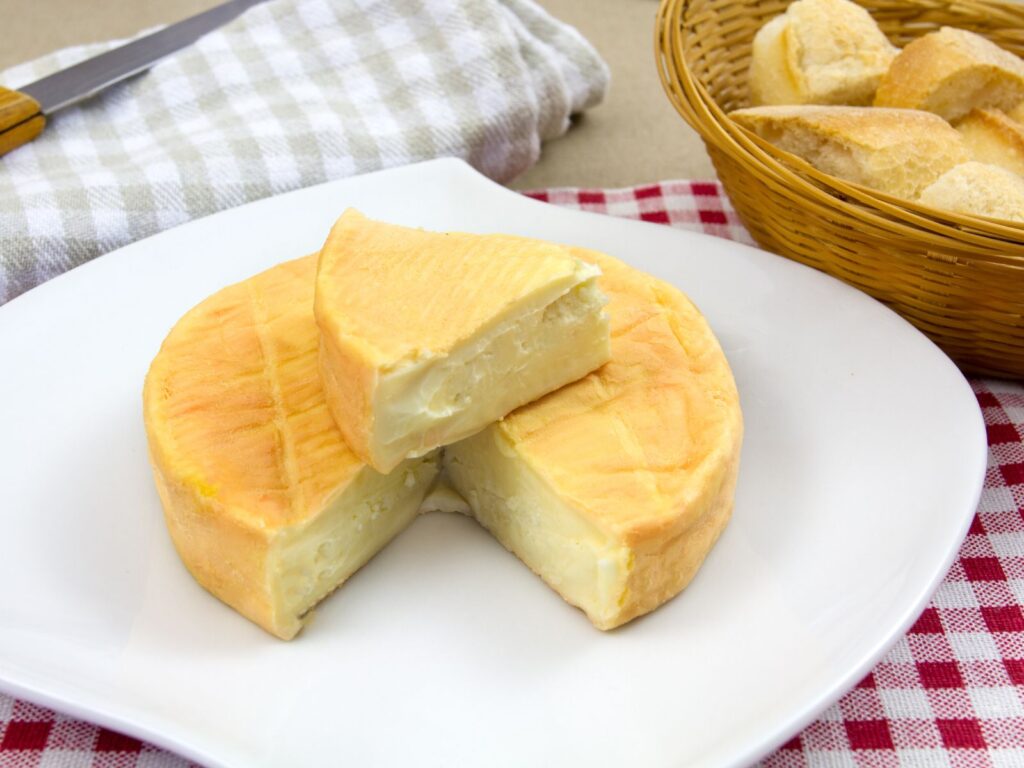 Small round washed rind cheese Munster on a white plate