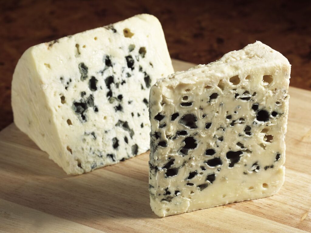2 slices of Roquefort soft blue cheese on a wooden board