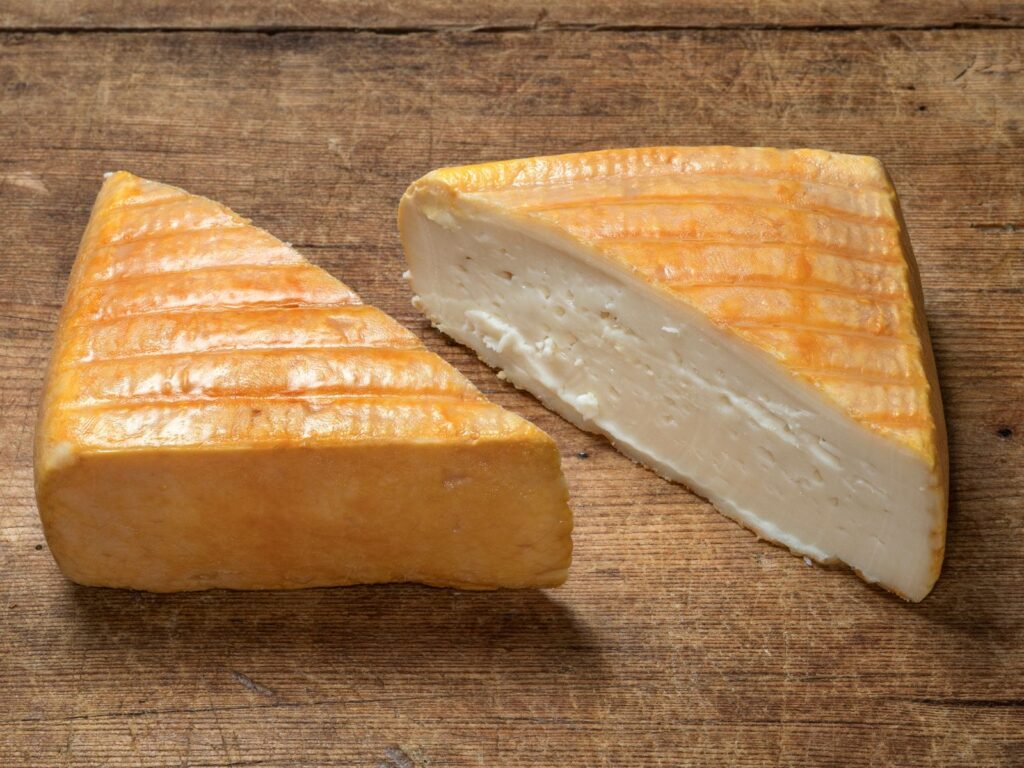Square shaped Vieux Boulogne cheese cut in half on a wood board