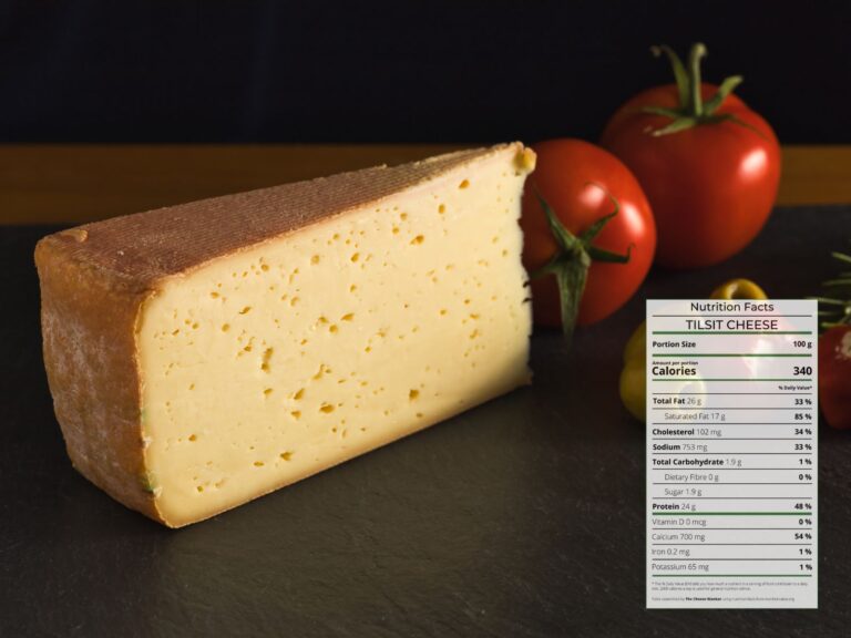 Wedge of Tilsit Cheese on a dark board with tomatoes