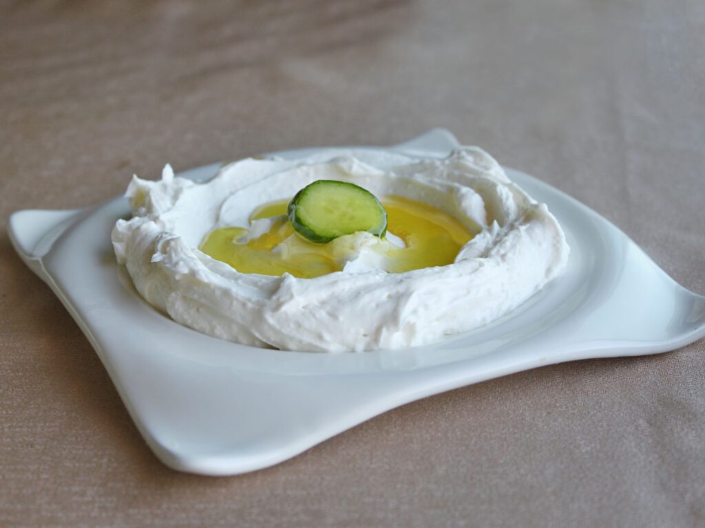 White plate of Labneh topped with olive oil and cucumber