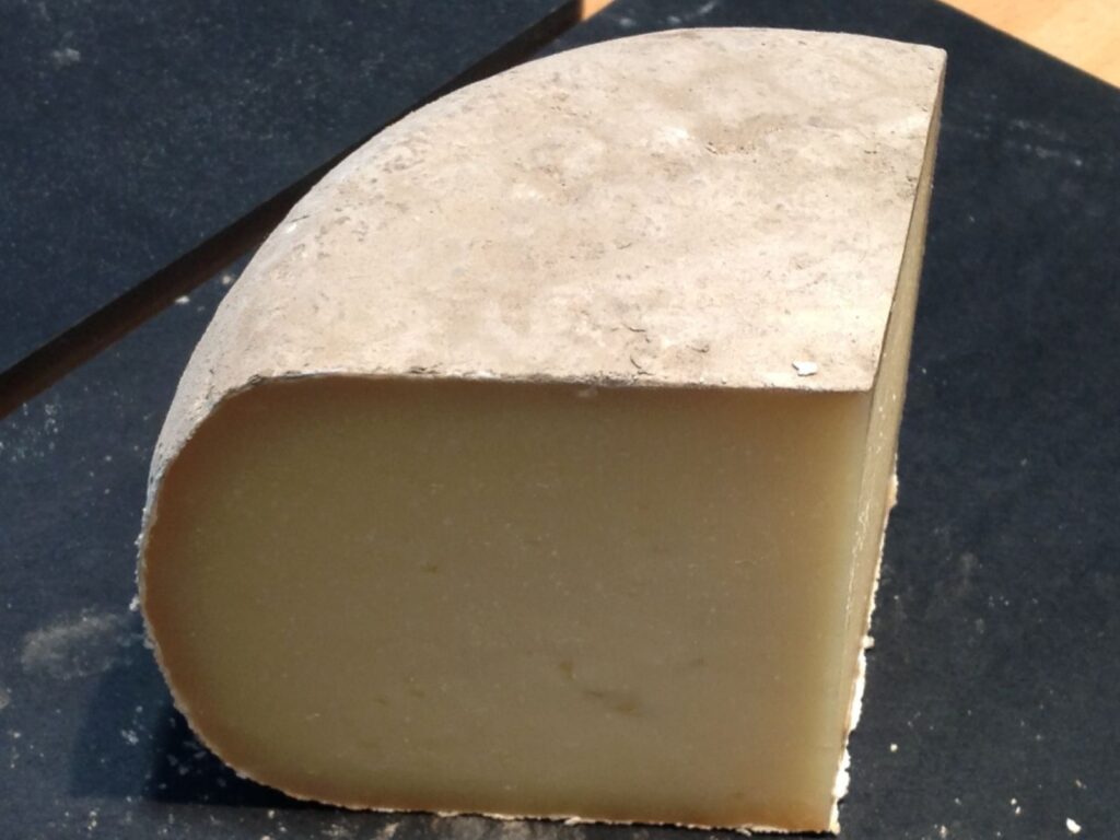 Wedge of Pecorino delle Balze Volterrane cheese on a slate board