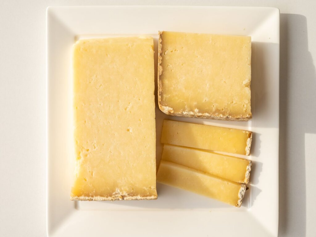 Slices of aged Cantal cheese on a white plate