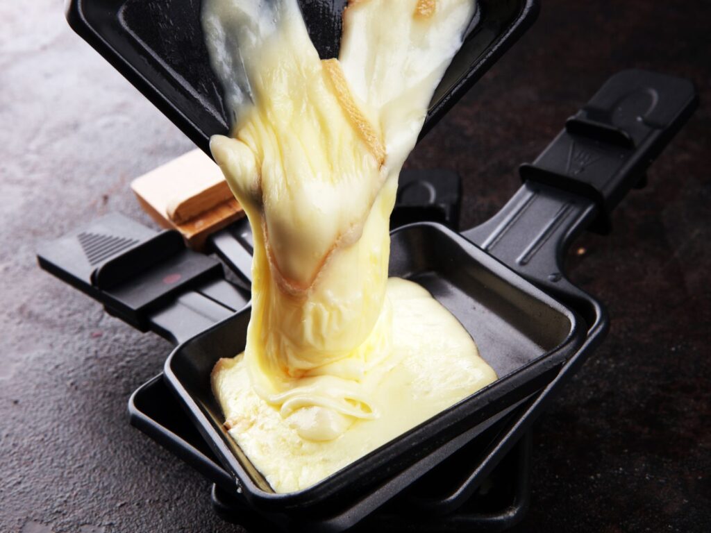 Pouring melted Raclette cheese onto black plate