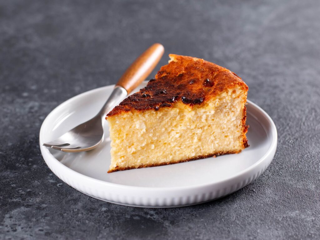 Slice of San Sebastián Cheesecake on a white plate with a metal fork