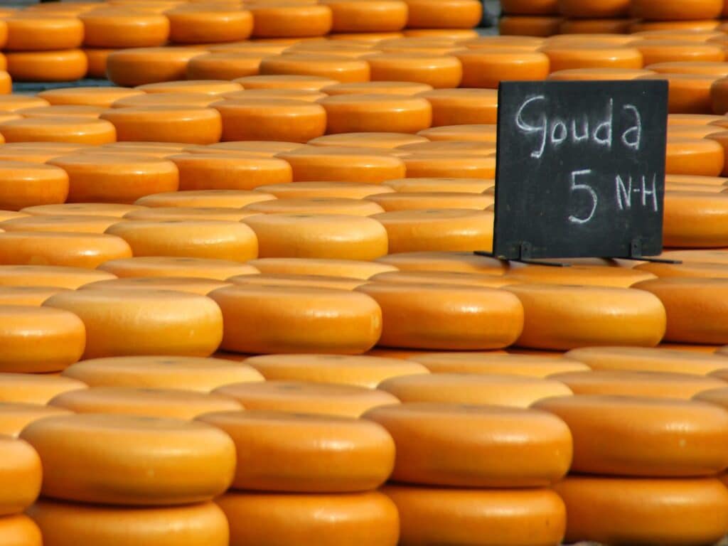 Stacks of orange Gouda cheese wheels at a market in the Netherlands