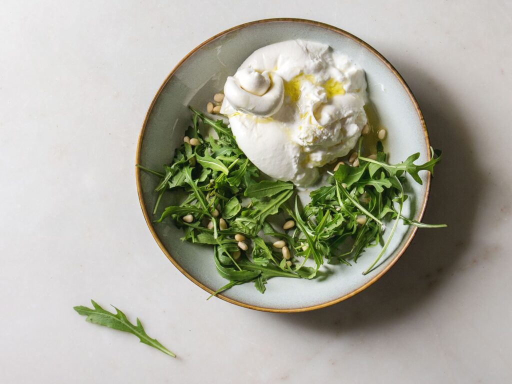 Cheesy parcel of Burrata on a grey plate with rocket leaves