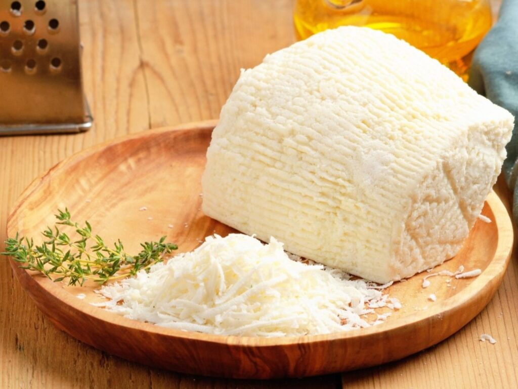 Hard whey cheese Ricotta Salata grated finely on wooden board