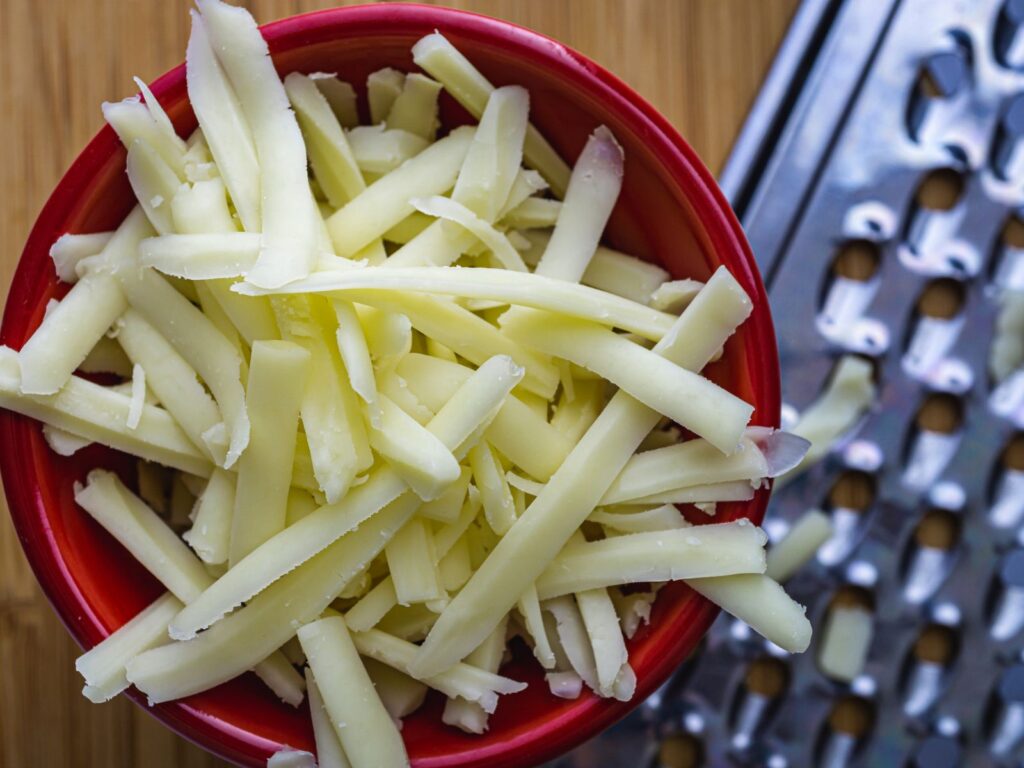 Shredded Monterey Jack cheese in a red bowl