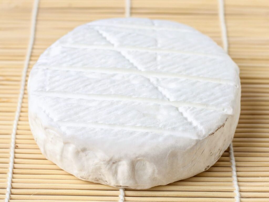 Soft white mould cheese draining on bamboo mat