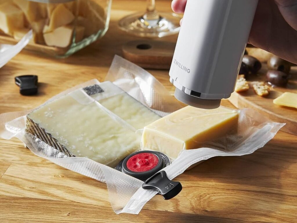 Handheld vacuum sealer used to seal wedges of hard cheese in plastic
